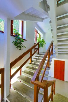 Stone staircase with wooden railing in the corridor of the hotel complex