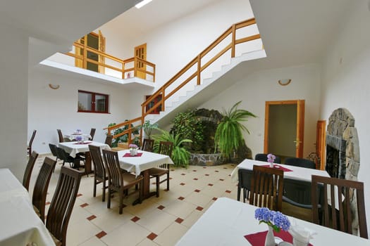 A beautiful two-story cafe. The design is executed in a white-brown style, with natural wooden handrails