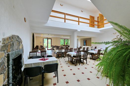 View of the second floor from the first on which is located a dining room with tables covered with white tablecloths and chairs.