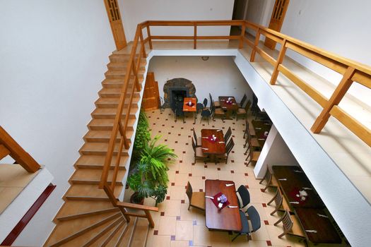 view from above to the banquet hall with tables chairs from the stairs with wooden banisters going down