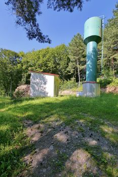 water tower near a house on a hill in a pine forest