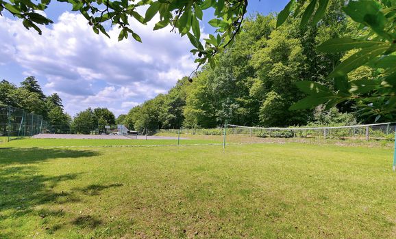 a green lawn in the forest for volleyball games with tensioned nets