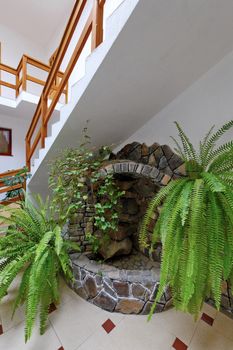 composition of an artificial fountain of ivy and fern under the stairs