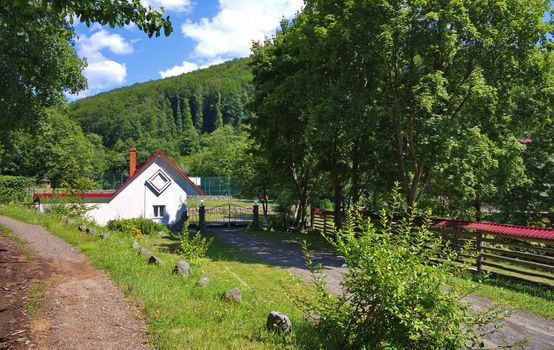 The road in the countryside rests against the gates of a closed area surrounded by wire mesh.
