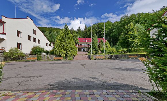 asphalt playground with benches for rest on the background of a hotel house and a green forest