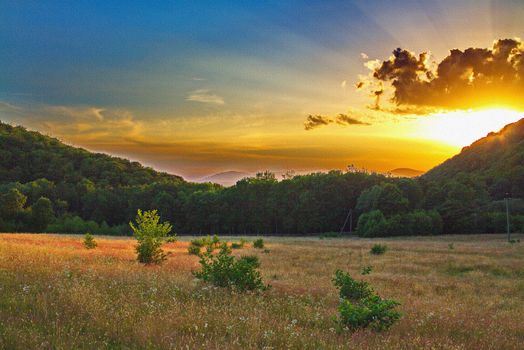 bright rays of the sunset break through the clouds at high mountains