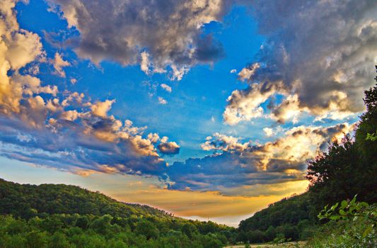 Yellow-blue sky, like the Ukrainian flag over the green hills around a large valley