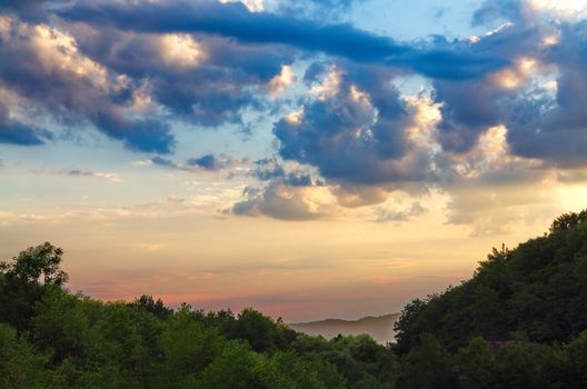 dark blue clouds of the evening sky floating above the forest to the horizon line