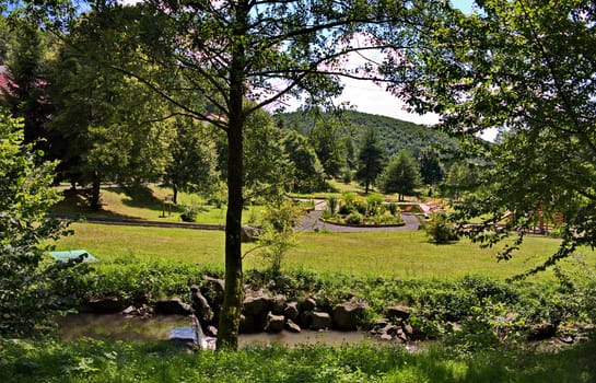 Decorative stone river rapids on the background of the beautiful green park zone of the hotel complex