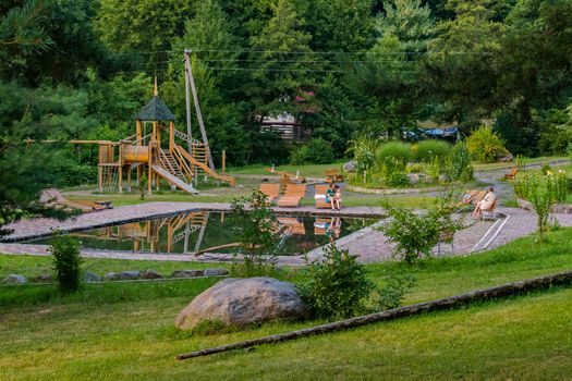 Father with a child on a bench in a park with a play area of wooden beams