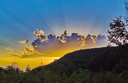 An exceptionally beautiful crescent playing yellow, blue and violet flowers in the clear sky above the green hills