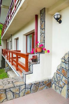 The wall of the building with railing around the windows and a three-tiered corner of the wall. On the steps formed on the corner are stacks of flowers