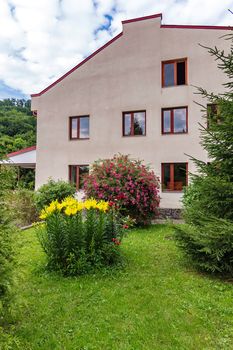 Beautiful scenery from the window the tenants see the house in the photo. Greenery, a flower bed with yellow and red flowers