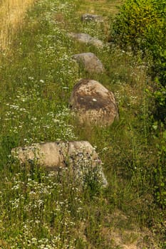 Large boulders on the grassy slope of the mountain in the rays of sunlight