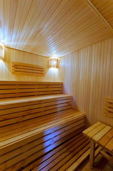 Three-tiered wooden benches with decorative lamps on the wall in a small bath