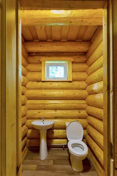 white toilet with washbasin in a wood-lighted sauna room