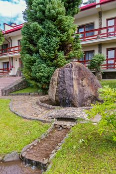 beautiful fountain with a large stone in the yard of the hotel complex in the mountains