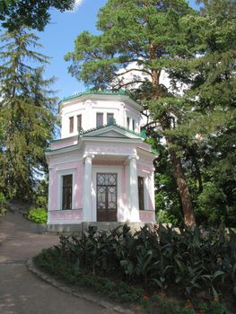 pink diamond-shaped building with a green roof against the background of spruces