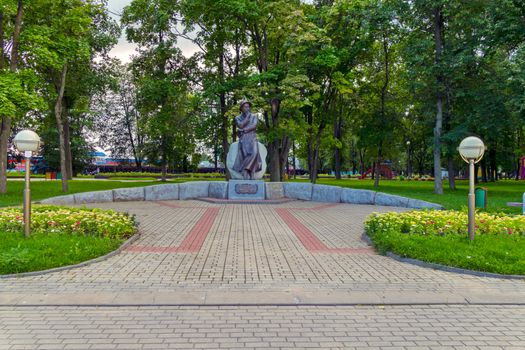 Bronze monument in the middle of the park with decorative flower beds and lanterns on the sides