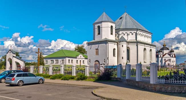 Parking in front of the entrance to the monastery grounds. With a church standing in the depths with domes and gold-cast crosses on them against a beautiful blue sky with clouds.