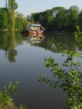 river tram and a long boat reflected in the pond