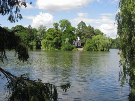 river with spruce and willow in the foreground and a building on the other shore
