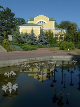 The building is yellow, reflected in a transparent blue lake, against the background of green trees