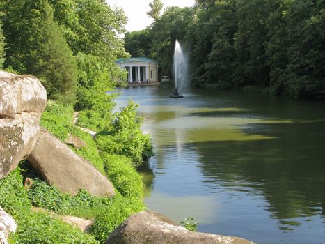 Rocky rocky shore of a transparent lake with a large hitting up fountain