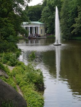 Tourists on a boat ride on a small lake with a huge fountain. Sofievsky Park, Uman, Ukraine