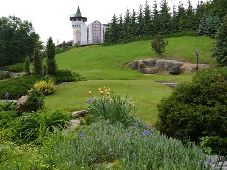 Green park with decorative bushes and beautiful trees against the backdrop of a modern hotel