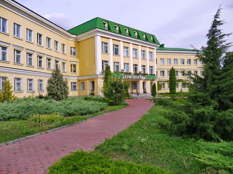 paths among green lawns leading to the entrance to a modern-looking hotel