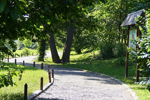 Stone-stitched promenade with informational sign amid a beautiful park zone