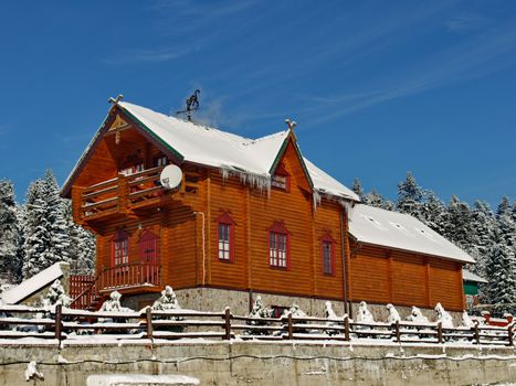 Luxury wooden cottage with a snow-covered roof and courtyard