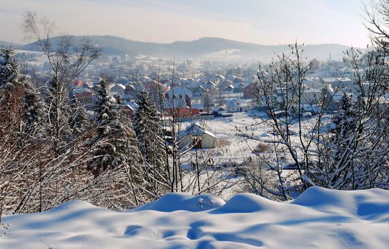Carpathian town is covered with white snow in a valley of mountains with transparent fog