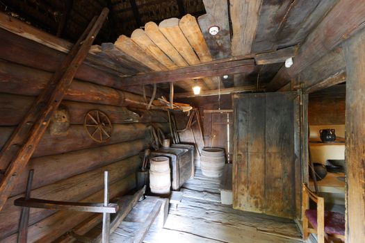 Entrance hall in a wooden hut with a staircase and wheel on the wall