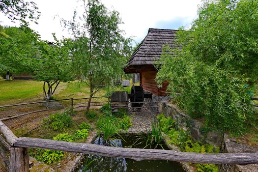 A small well with a wheel under the roof of a wooden house