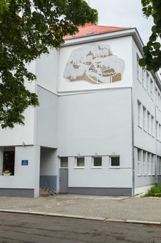 Entrance to a three-story building with white-gray walls and a red roof