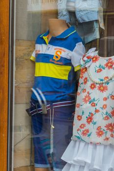 glass shop window with headless mannequins dressed in bright clothes