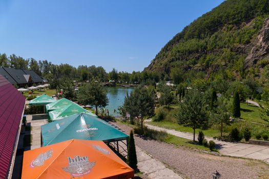 Beach green area with tents, awnings and sunbeds at the green transparent mountain lake