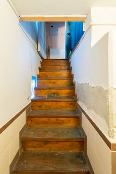 A narrow staircase in the room leading up with wooden stairs