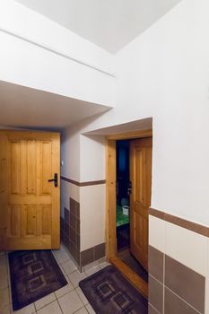 Wooden doors leading to the room from the corridor lined with tiles