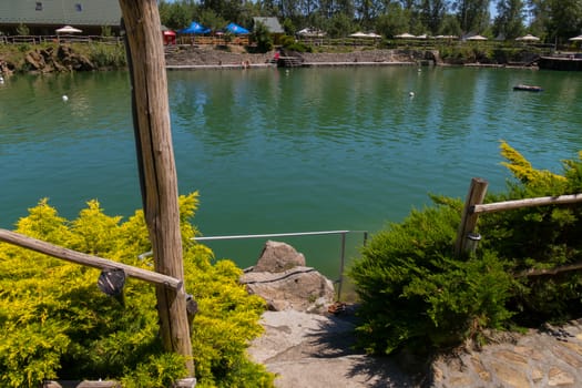 A picturesque view of a decorative mountain clear lake with swimming and sunbathing tourists