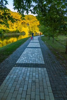 Paved multi-colored tile walking alley on the shore of a large transparent decorative lake