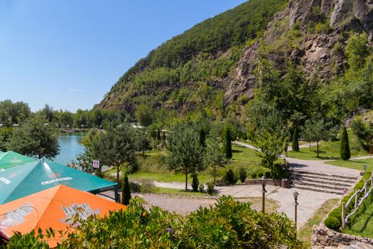 summer cafe and trees on the shore of the lake at the foot of the mountain