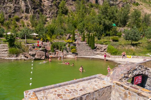 tourists swimming in an artificial reservoir with steps of stone between low mountains