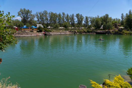 Park area for holidaymakers with a green lake, a comfortable beach and umbrellas. A place for family rest