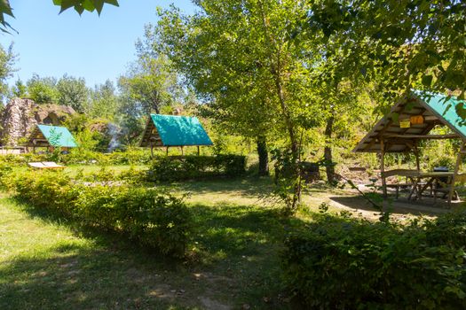 Convenient gazebos with a green roof and barbecue facilities against the backdrop of a rocky green mountain...