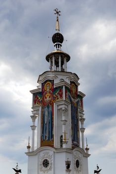 A beautiful high church building with saints' faces on the walls with a dome and beautiful architecture against a sky with clouds.