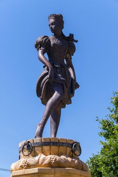 Bronze statue of a girl pressing grapes in a wooden bucket