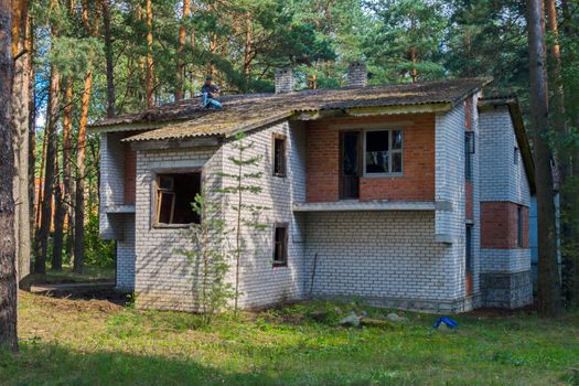 Unfinished brick two-storey house in the background of a pine forest